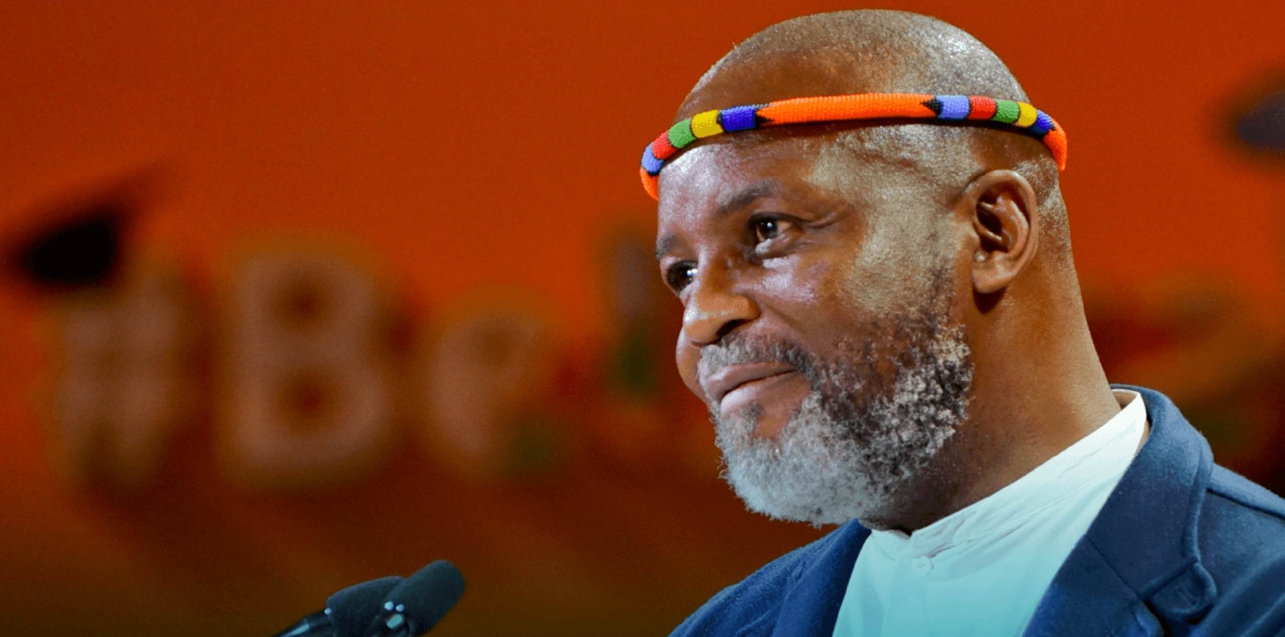 Thebe Ikalafeng speaking, wearing a beaded headband